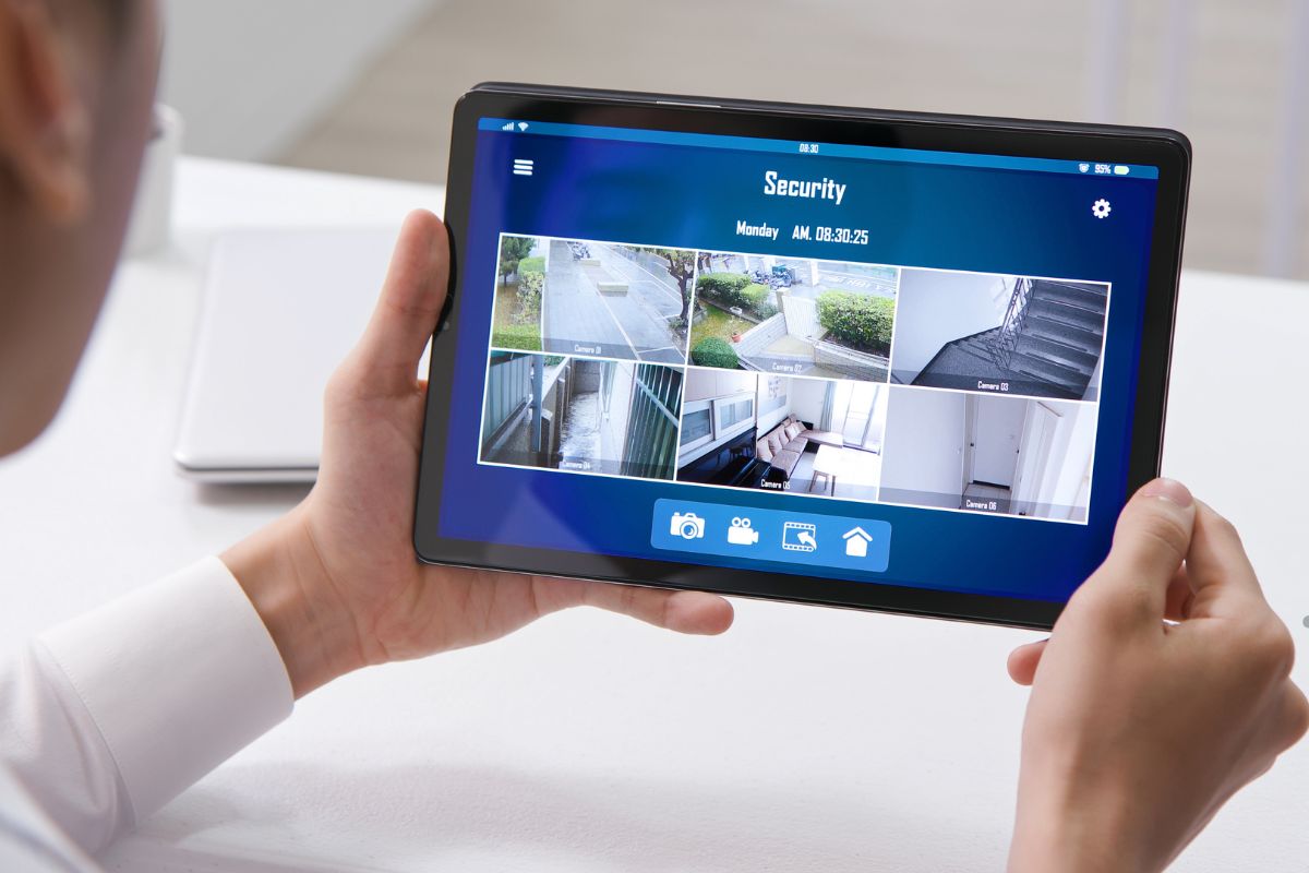 A man displays a tablet showing a home security camera feed, emphasizing modern home surveillance technology.