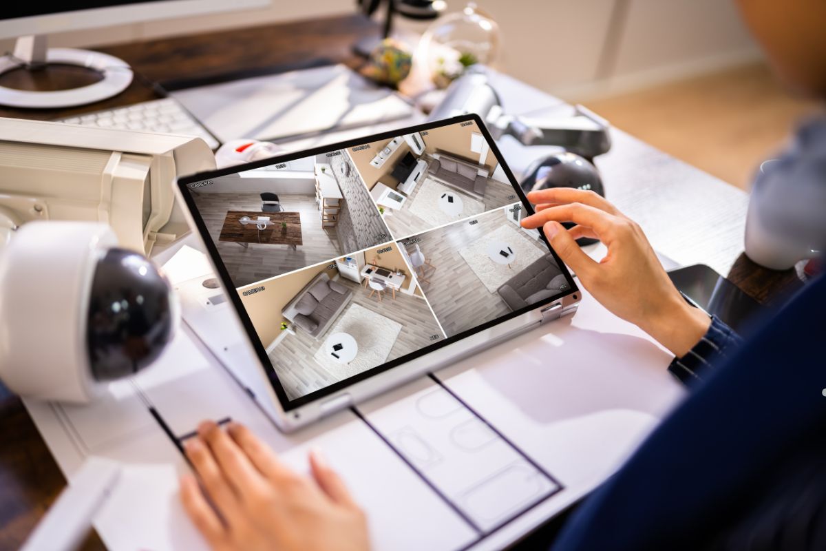 A person sits on a couch, using a tablet to watch a video of their home interior.