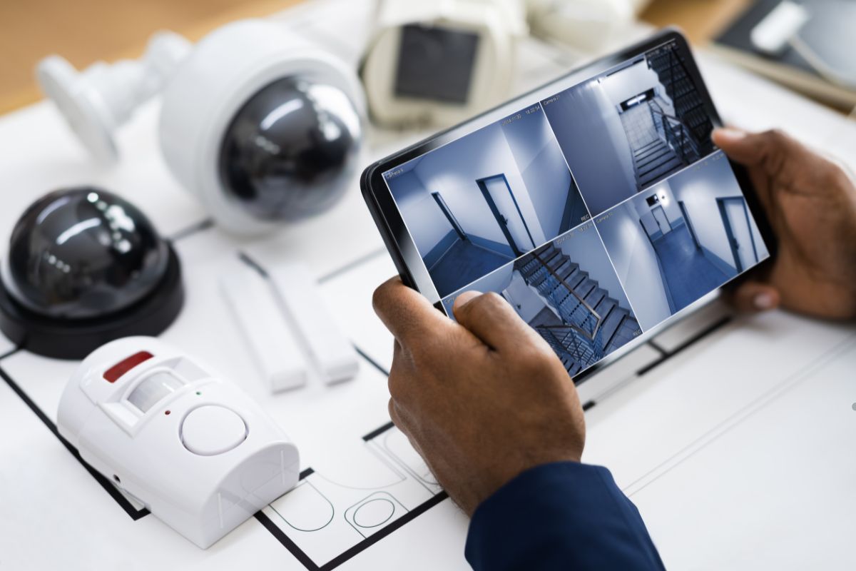 A person viewing home security camera feeds on a tablet, focused on the screen with various camera angles displayed.
